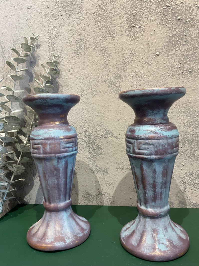 K&ouml;nnte beinhalten: Zwei dekorative Kerzenhalter im antiken Stil mit Used-Look. Die Halterungen sind in Blau-, Braun- und Lilat&ouml;nen gehalten. Sie weisen ein griechisches Schl&uuml;sselmuster und einen geriffelten Sockel auf. H&ouml;he ca. 15 cm.