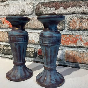 K&ouml;nnte beinhalten: Zwei blau-braune dekorative Kerzenhalter mit einem Used-Look-Finish. Die Halter haben eine klassische Form mit breitem Sockel, schlankem K&ouml;rper und ausgestellter Oberseite. Die Halter sind aus robustem Material gefertigt und f&uuml;r verschiedene Einrichtungsstile geeignet.