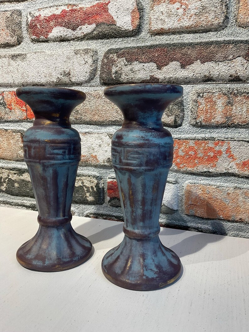 K&ouml;nnte beinhalten: Zwei blau-braune dekorative Kerzenhalter mit einem Used-Look-Finish. Die Halter haben eine klassische Form mit breitem Sockel, schlankem K&ouml;rper und ausgestellter Oberseite. Die Halter sind aus robustem Material gefertigt und f&uuml;r verschiedene Einrichtungsstile geeignet.