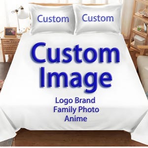 Könnte beinhalten: Weißes Bettwäsche-Set mit zwei Kissenbezügen, jeweils mit dem Wort "Custom" in Blau. Die Bettdecke zeigt die Worte "Custom Image" in großen blauen Buchstaben, darunter "Logo Brand Family Photo Anime".