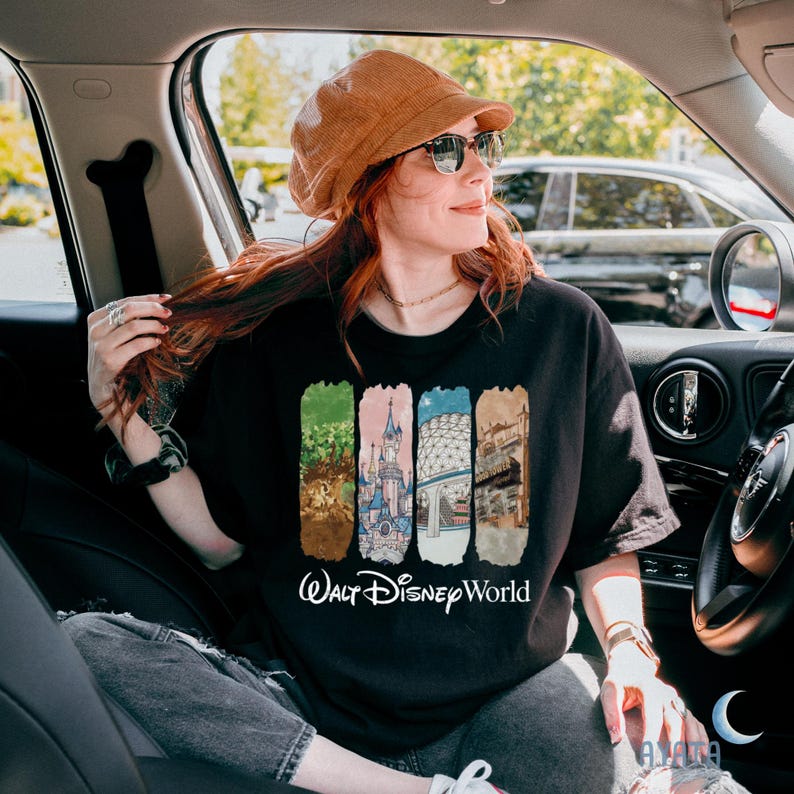 Puede incluir: Camiseta negra con un colorido gr&aacute;fico de Walt Disney World. El dise&ntilde;o presenta cuatro paneles verticales con im&aacute;genes ic&oacute;nicas del parque y las palabras "Walt Disney World" en escritura blanca. La persona de la imagen lleva un sombrero marr&oacute;n y gafas de sol.