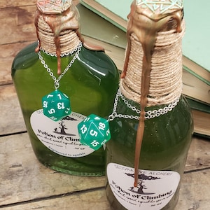 May include: Two green glass potion bottles with rope-wrapped necks and decorative wax seals. Each bottle has a silver chain with a green D20 die. The labels read "Potion of Climbing" and "Decorative Alchemy".
