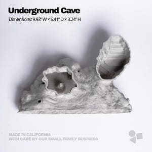 Pu&ograve; includere: Un modello di grotta sotterranea grigio chiaro testurizzato con due aperture distinte. Il testo recita Underground Cave, Dimensions: 9.93" W x 6.41" D x 3.24" H, e Made in California with care by our small family business.