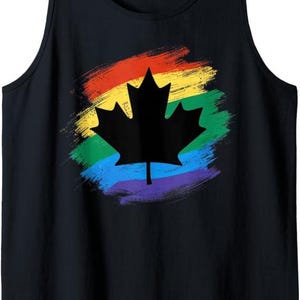 May include: A black tank top featuring a central graphic of a solid black maple leaf silhouette centered over a circular, brushstroke-style rainbow pattern. The design incorporates horizontal bands of red, orange, yellow, green, blue, and purple.