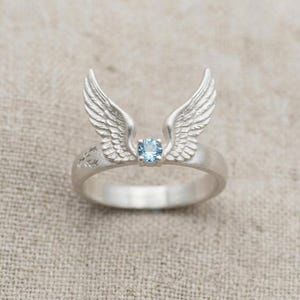 May include: A white ceramic mug with a black handle and the text "But First, Coffee" in a black, handwritten-style font. The mug is on a white surface.