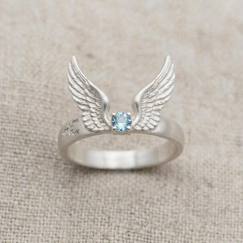 May include: A white ceramic mug with a black handle and the text "But First, Coffee" in a black, handwritten-style font. The mug is on a white surface.