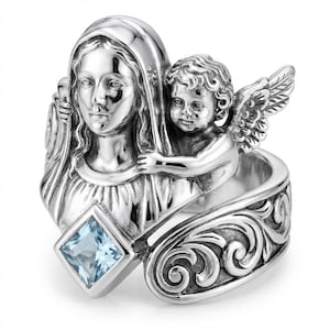 May include: A silver ring featuring a detailed depiction of a religious figure and an angel. The ring has a square, light blue gemstone and ornate scrollwork on the band. The angel has detailed wings and is positioned next to the religious figure.