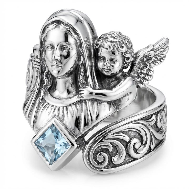 May include: A silver ring featuring a detailed depiction of a religious figure and an angel. The ring has a square, light blue gemstone and ornate scrollwork on the band. The angel has detailed wings and is positioned next to the religious figure.