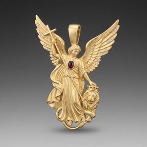 May include: A gold-colored pendant featuring an angel with outstretched wings, holding a cross and standing beside a crowned lion. The angel's dress has a red gemstone. The wings are adorned with small, clear stones. The pendant has a loop for a chain.