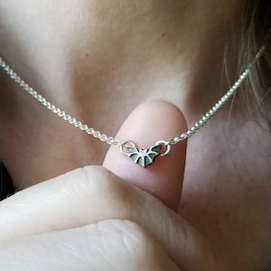 May include: A silver chain necklace with a small bat pendant.