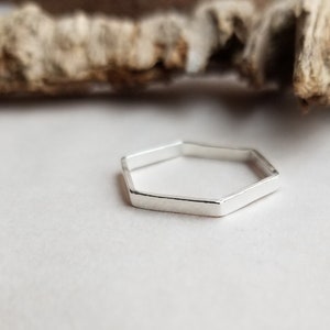 May include: A silver hexagonal ring with a smooth, polished finish.