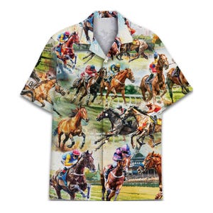 May include: Short-sleeved button-down shirt featuring a watercolor print of a horse race. The design includes jockeys on horseback, racing on a green track. The shirt has a white collar and a button-up front.