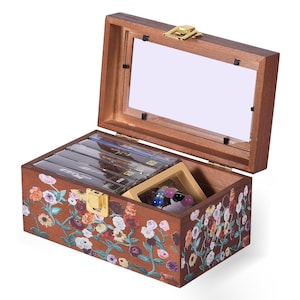 May include: Open wooden jewelry box with a hinged lid and a clear glass top. The box is decorated with colorful floral patterns and contains jewelry and cassette tapes. The box has a gold-colored clasp.