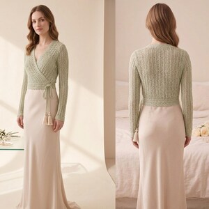May include: A light green, long-sleeved wrap top with a V-neck and tie closure, paired with a long, cream-colored skirt. The top features a delicate knit pattern and is accessorized with matching tassels. The outfit is suitable for formal occasions.