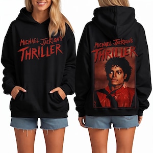 May include: Black hoodie with the red text "MICHAEL JACKSON'S THRILLER". The back of the hoodie shows a portrait of Michael Jackson in a red jacket. The hoodie has a hood and a front pocket.