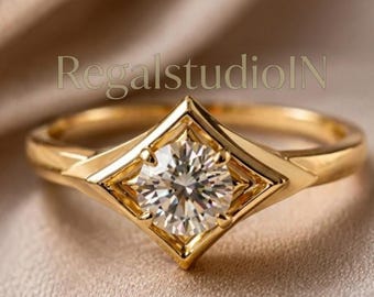 May include: A gold ring featuring a round brilliant-cut clear gemstone set within a diamond-shaped bezel. The band is smooth and polished gold. The text RegalstudioIN is visible in the background. The design highlights a geometric frame.