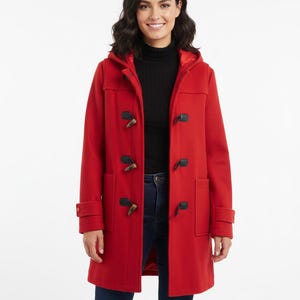 May include: A red hooded duffel coat with toggle closures and two front pockets. The coat features a classic design with a hood and long sleeves. The coat is made of a warm material, perfect for cold weather. The model is wearing blue jeans and a black turtleneck.