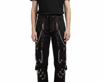 Pantalones cargo negros y rojos con costuras en contraste, estilo punk gótico con cadenas plateadas y correas de bondage, ropa técnica para hombre, estilo urbano alternativo.