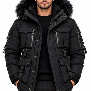 May include: A black winter parka featuring a hood with faux fur trim, multiple utility pockets with zippers and snap buttons, D-ring hardware, and adjustable straps. The jacket has a front zipper closure and ribbed cuffs on the sleeves.