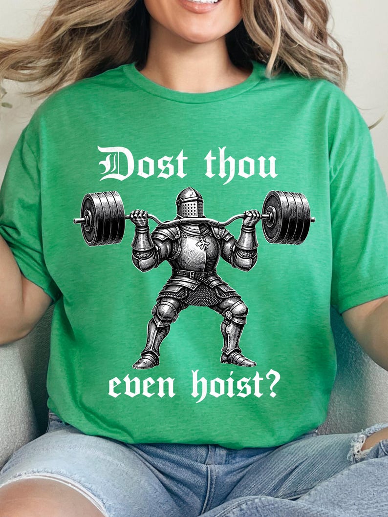 K&ouml;nnte beinhalten: Gr&uuml;nes T-Shirt mit einer Schwarz-Wei&szlig;-Illustration eines Ritters, der eine Langhantel hebt. Der Text "Dost thou even hoist?" ist oberhalb und unterhalb des Ritterbildes in einer mittelalterlichen Schrift gedruckt.