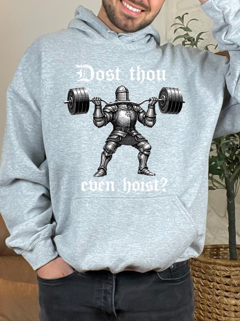 K&ouml;nnte beinhalten: Hellgrauer Kapuzenpullover mit dem Text "Dost thou even hoist?" &uuml;ber einer Schwarz-Wei&szlig;-Illustration eines Ritters, der Gewichte hebt. Der Ritter tr&auml;gt eine volle R&uuml;stung und h&auml;lt eine Langhantel.