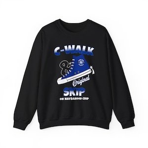 May include: Black sweatshirt featuring a blue high-top trainer graphic. The graphic includes the text "C-WALK", "Original", and "SKIP" in white and blue. The sweatshirt also has the text "ON NAYBAHOOD CRIP".