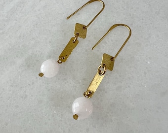 May include: A pair of gold earrings with white round stones and a geometric design.
