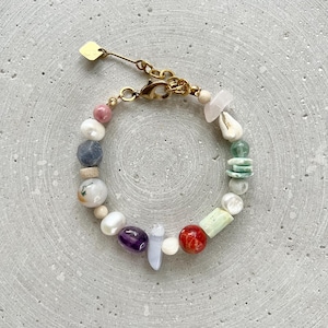 May include: A colourful beaded bracelet with a gold clasp. The bracelet features a variety of stones, including amethyst, turquoise, and rose quartz.