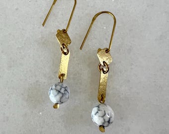 May include: Gold dangle earrings with white marble-like beads and gold geometric shapes.