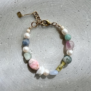 Könnte beinhalten: Ein goldfarbenes Kettenarmband mit verschiedenen bunten Steinen, darunter rosa, blau, grün und weiß. Das Armband hat einen Karabinerverschluss.