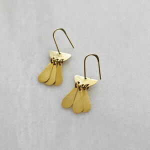 May include: A pair of gold dangle earrings with a triangular top and three teardrop-shaped pendants.