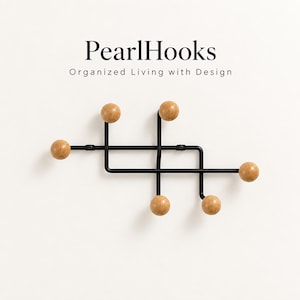 Peut inclure: Un porte-manteau mural composé d'une structure en métal noir au design géométrique et de cinq crochets en forme de boules en bois brun clair. Le texte PearlHooks Organized Living with Design est inscrit au-dessus en lettres noires.