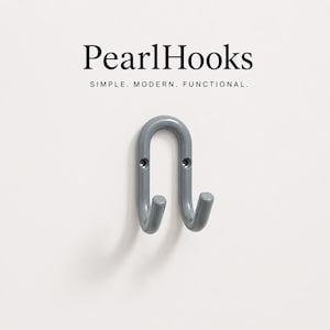 Puede incluir: Un gancho de pared de metal gris en forma de U con dos puntas y dos orificios para tornillos de montaje. Sobre el gancho, el texto dice PearlHooks y SIMPLE. MODERN. FUNCTIONAL. El gancho tiene un acabado liso y brillante y un diseño curvo.