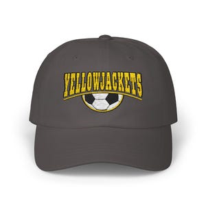 May include: A dark gray baseball cap with an embroidered yellow and white soccer ball and the text "YELLOWJACKETS" in yellow.