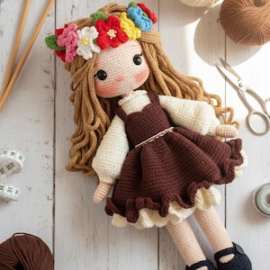 May include: A handcrafted crochet doll with long brown hair and a floral crown. The doll is dressed in a brown dress with a white blouse and black shoes. Knitting needles, yarn, and scissors are visible.