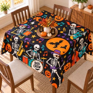 May include: A black tablecloth featuring a colorful Halloween pattern of skeletons playing musical instruments, orange pumpkins, bats, and musical notes. One skeleton plays a drum set with the text BOO CREW printed on the bass drum head.