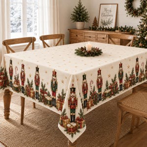 May include: A rectangular tablecloth with a cream-colored base featuring a repeating pattern of nutcracker figures, wrapped gift boxes, and candy canes along the edges, accented by small gold stars scattered across the top surface.