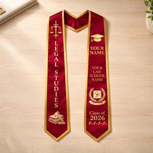 May include: A maroon graduation sash with gold trim and text. The left side reads "LEGAL STUDIES" with a gavel and books icon. The right side has space for "YOUR NAME" and "YOUR LAW SCHOOL NAME", with "Class of 2026" at the bottom.