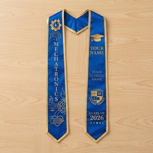 May include: A blue and gold graduation sash with the word "MECHATRONICS" printed vertically. The sash has a gold trim and features a graduation cap graphic, the text "YOUR NAME", "YOUR SCHOOL NAME", and "CLASS OF 2026".
