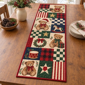 May include: A rectangular quilted table runner featuring a patchwork design with teddy bears, rocking horses, drums, stars, and wreaths. The fabric displays red, green, and cream colors with plaid and checkered patterns, finished with a red border.
