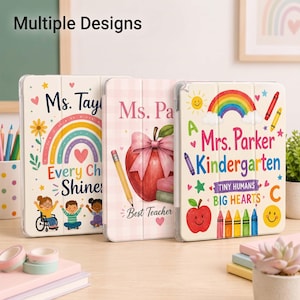 May include: Three tablet cases featuring colorful designs for teachers. The left case shows a rainbow and children with the text Ms. Taylor Every Child Shines. The middle case features an apple and pencil with Ms. Parker Best Teacher. The right case displays a rainbow, apple, and crayons with Mrs. Parker Kindergarten Tiny Humans Big Hearts.
