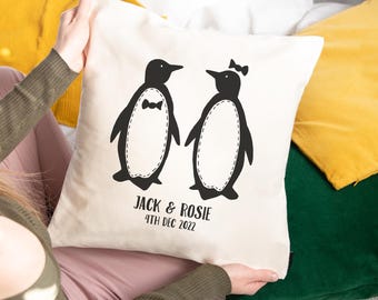 May include: White pillow with a black illustration of two penguins wearing a bow tie and a bow. The text "Jack & Rosie 4th Dec 2022" is printed below the penguins.