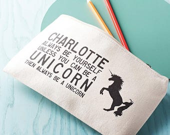 Peut inclure: Une trousse à crayons en toile blanche avec un motif de licorne noire et le texte "CHARLOTTE ALWAYS BE YOURSELF UNLESS YOU CAN BE A UNICORN THEN ALWAYS BE A UNICORN".