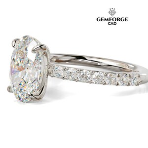 May include: A silver engagement ring with a large oval-cut diamond as the centerpiece. The band features smaller diamonds set along the top half. The ring is set against a white background. The logo "GEMFORGE CAD" is in the upper right corner.