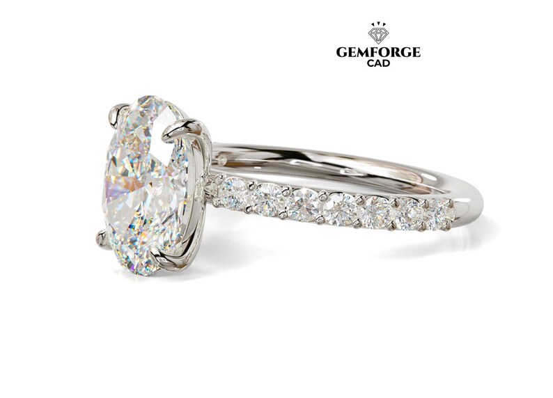 May include: A silver engagement ring with a large oval-cut diamond as the centerpiece. The band features smaller diamonds set along the top half. The ring is set against a white background. The logo "GEMFORGE CAD" is in the upper right corner.