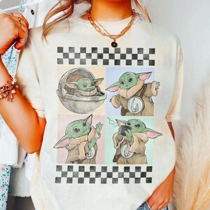 Puede incluir: Camiseta color crema con un dise&ntilde;o gr&aacute;fico de cuatro paneles de Grogu de The Mandalorian. Cada panel muestra a Grogu en diferentes poses, con un patr&oacute;n de tablero de ajedrez arriba y abajo. La camiseta tiene cuello redondo.