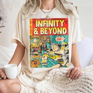 Może przedstawiać: Kremowa koszulka z grafiką w stylu komiksowym z napisem "INFINITY & BEYOND" w kolorze czerwonym i ż&oacute;łtym. Grafika zawiera wizerunki postaci i tekst "NOT TODAY ZURG!"