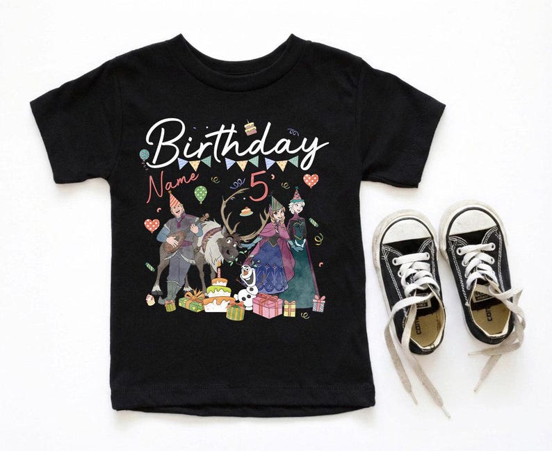 May include: Black short-sleeved t-shirt with a colorful graphic featuring characters and the text "Birthday Name 5". The graphic includes a cake, presents, and a banner. Black canvas sneakers with white laces are next to the shirt.