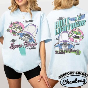 May include: A light blue t-shirt featuring Buzz Lightyear graphics. The front displays Buzz Lightyear, a spaceship, and the text Space Ranger. The back shows Buzz Lightyear, a spaceship, the text Buzz Lightyear, and To Infinity & Beyond.