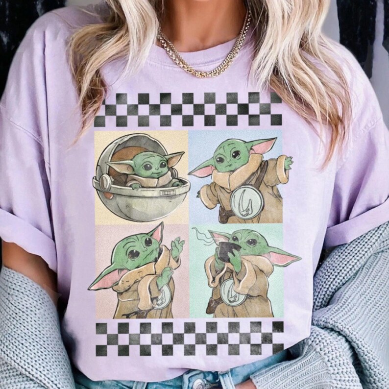 Puede incluir: Camiseta lila claro con un dise&ntilde;o de cuatro paneles de un personaje alien&iacute;gena verde en varias poses. El dise&ntilde;o est&aacute; enmarcado por un patr&oacute;n de cuadros blanco y negro en la parte superior e inferior.